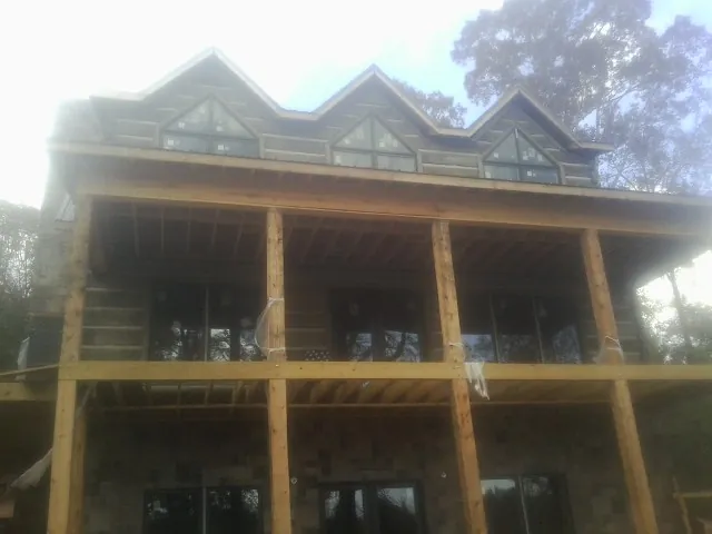 Dormers and porch framing on a large log home under construction — Roof Coating work by our crew in Fond Du Lac