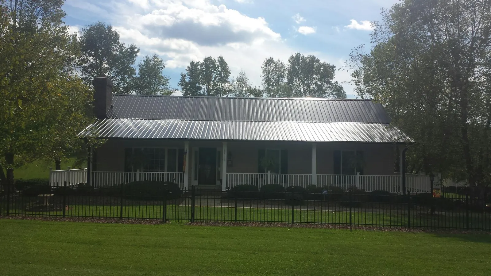 Gray metal roof on a brick ranch with a full width front porch — Gutter Guard Installation work by our crew in Fond Du Lac