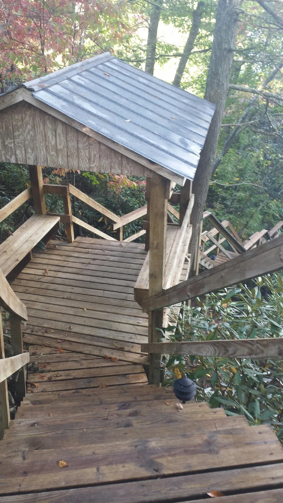 Metal roofed shelter over wooden steps on a wooded walkway — Skylight Repair & Installation work by our crew in Fond Du Lac