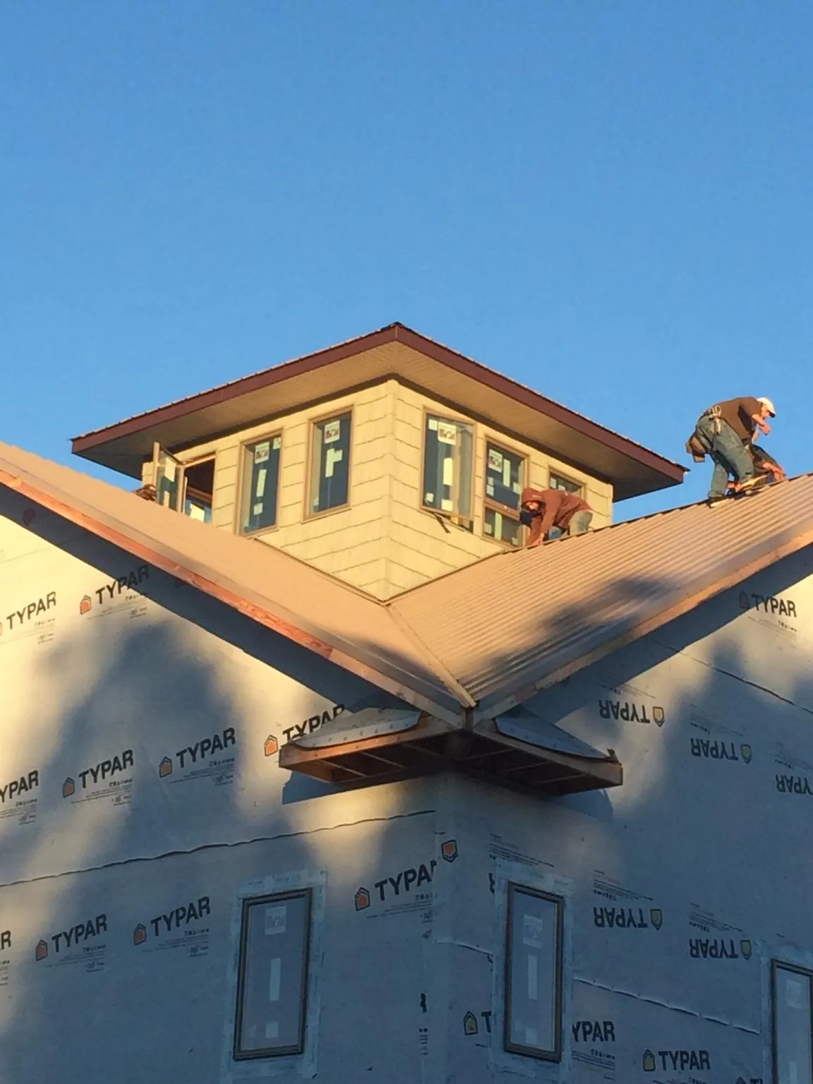 Roofers working around a rooftop cupola on a new metal roof at sunset — Roof Waterproofing in Fond Du Lac by Roofing Brothers